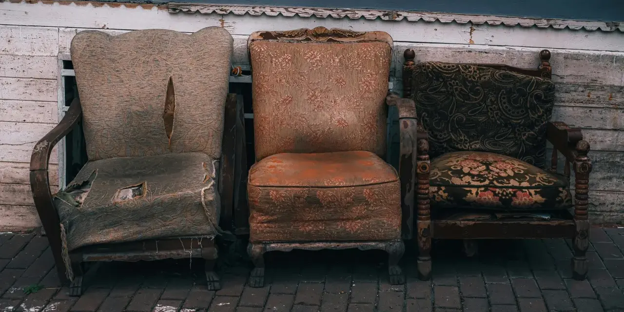 Trzy zniszczone fotele, które wyglądają, jakby czekały na to, gdzie wywieźć stare meble.