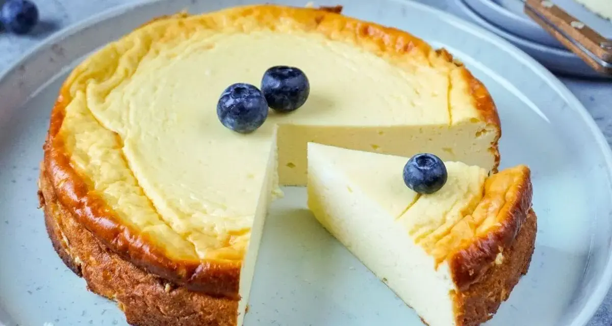 Ein köstlicher low carb Kuchen mit Blaubeeren, der auf einem Teller serviert wird. Ein Stück ist bereits herausgeschnitten.
