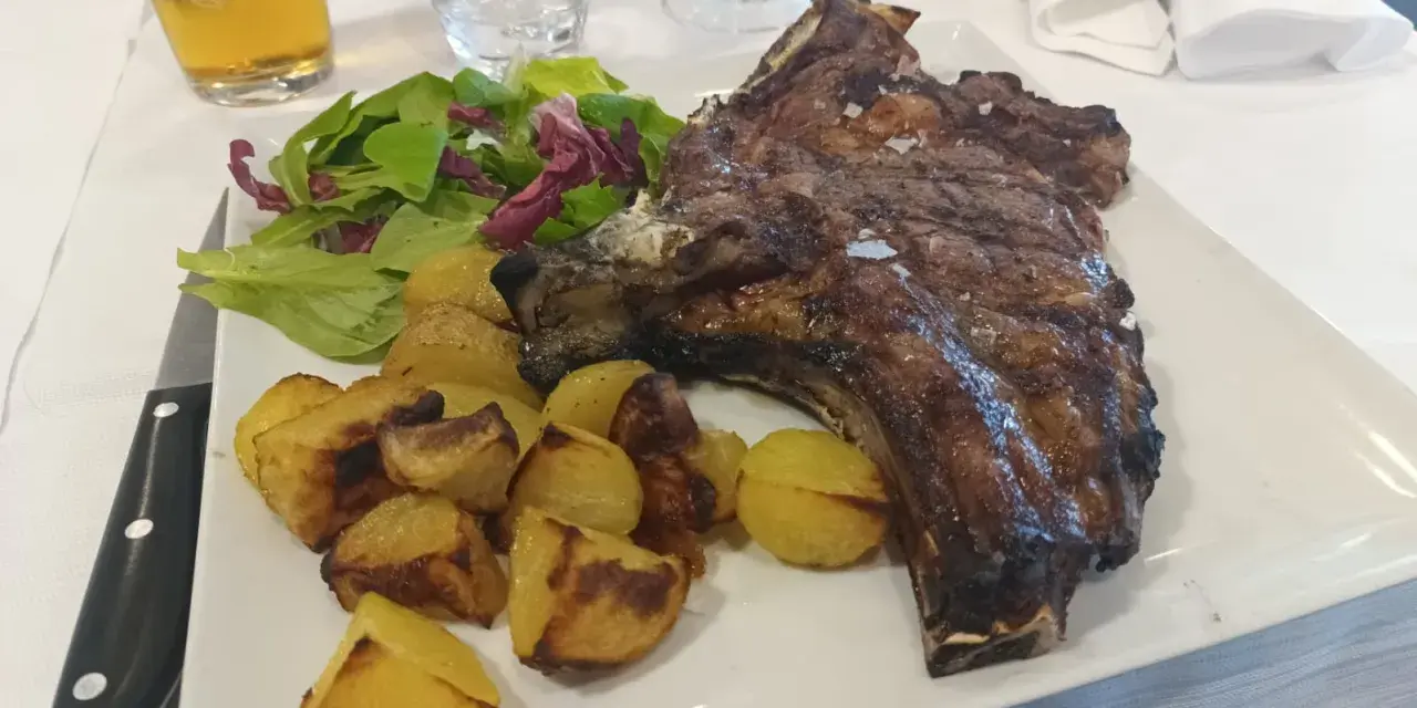 Succulenta costata di manzo alla griglia, servita con patate arrosto croccanti e un'insalata fresca. Un piatto da vero intenditore.