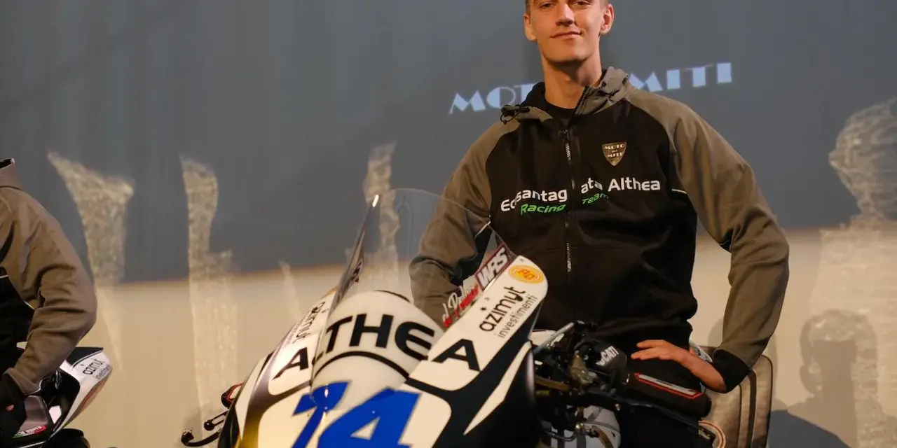 Piotr Biesiekirski, młody kierowca wyścigowy, pozuje obok swojego motocykla z numerem 14.
