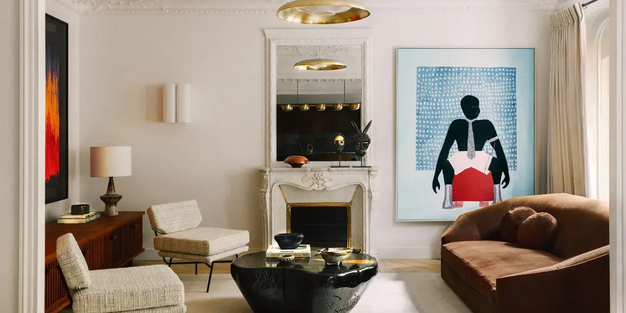 Un dormitorio eclectico con sofá marrón, dos sillones de tweed, mesa de centro de piedra negra, chimenea de mármol y arte abstracto vibrante.