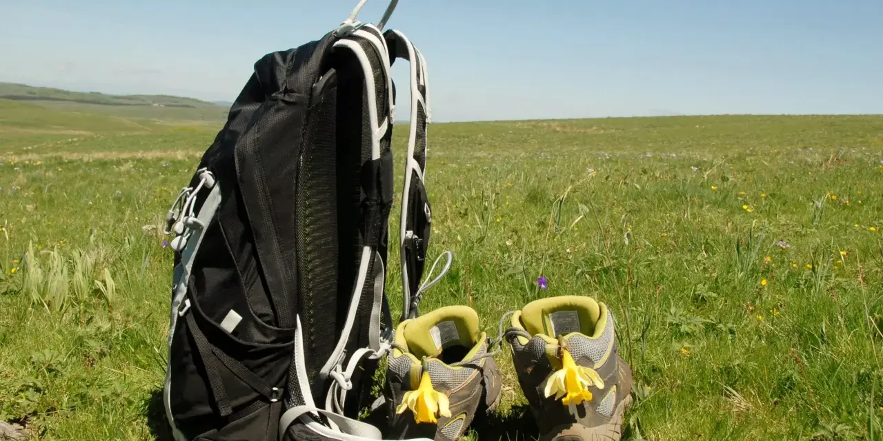 Sac à dos et chaussures de randonnée ornées de jonquilles, prêts pour une randonnée sur l'Aubrac.