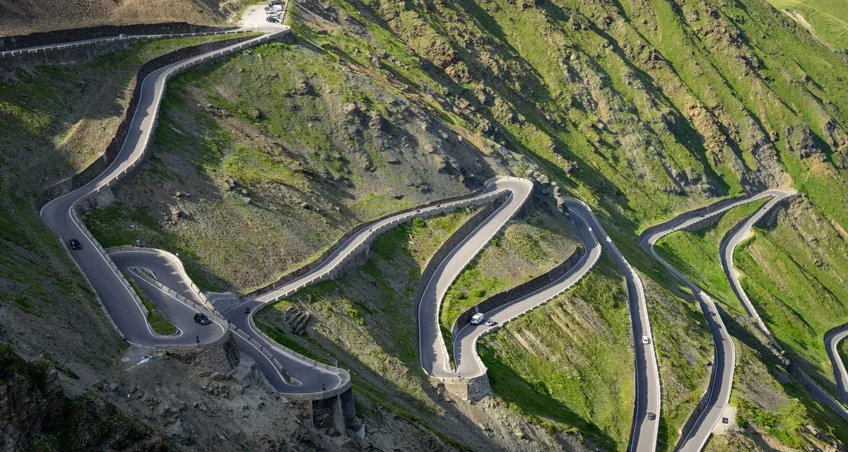 Strada tortuosa che sale verso il passo più alto d'Europa, con tornanti stretti e panorami mozzafiato.