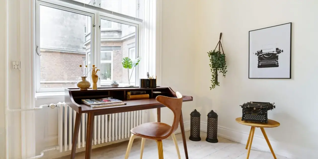 Ett elegant skrivbord i oljad ek med en läderklädd stol. En gammal skrivmaskin står på ett litet sidobord.