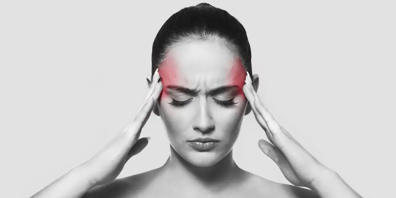 Donna con un'aura occhio rossa sulla fronte, che si tiene le tempie con le mani, sofferente.