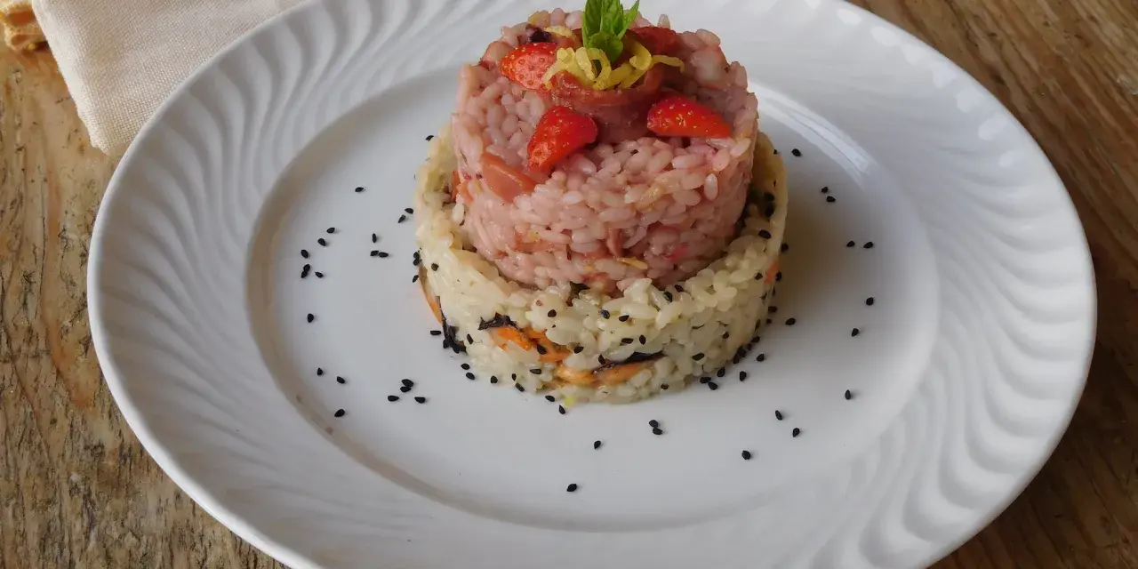 Due torri di riso, una rosa con fragole e menta, l'altra bianca con verdure e semi neri. Un piatto che ricorda la crema di riso.