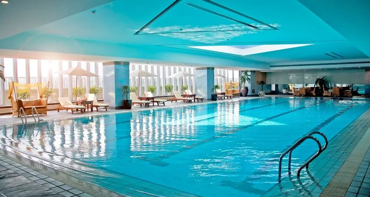 Relaks w hotelu z basenem na Podlasiu. Długi, błękitny basen z leżakami i parasolami, idealny na wakacje.