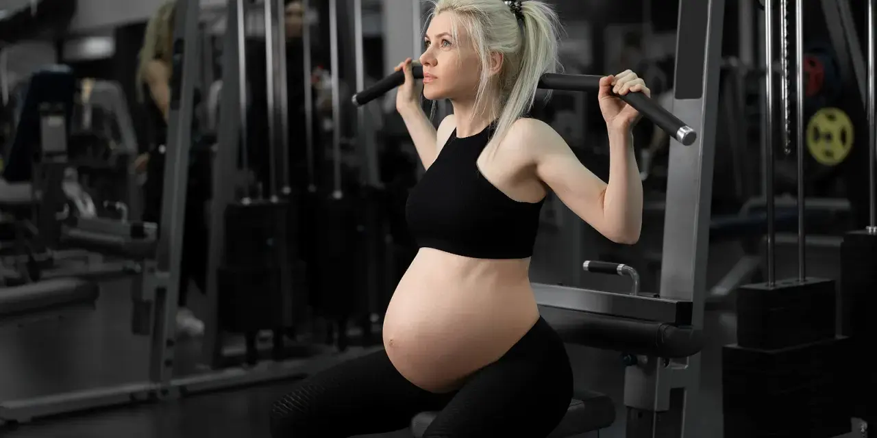 Gravid kvinna tränar marklyft i gym.