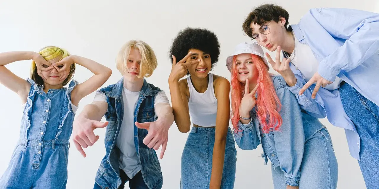 Ragazzi con un look anni '90, tutti vestiti di jeans, fanno pose divertenti.
