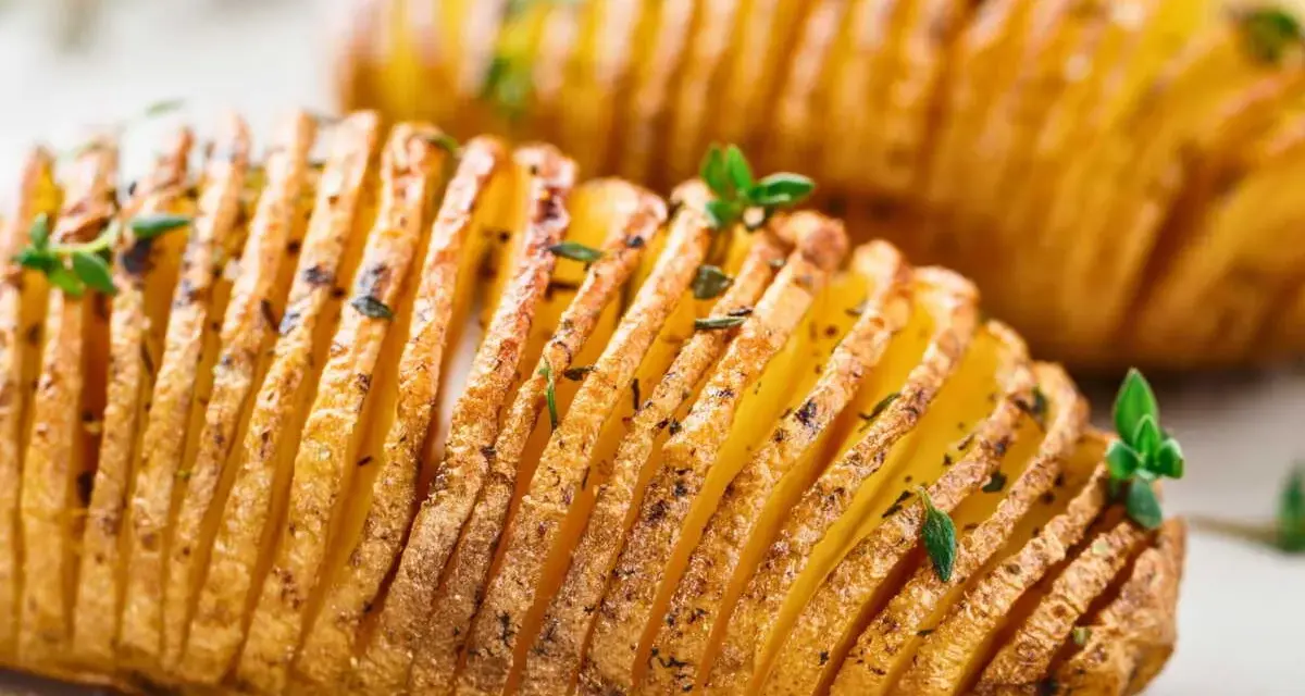 Deux pommes de terre hasselback dorées et croustillantes, garnies d'herbes fraîches. Un délice visuel et gustatif.
