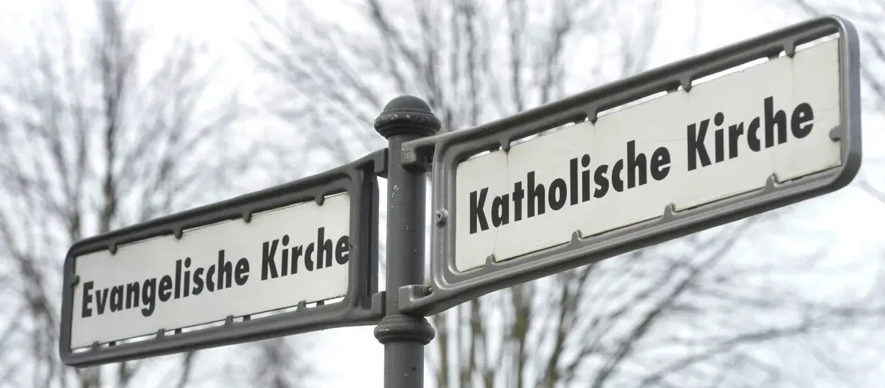 Straßenschilder weisen den Weg zur Evangelischen und Katholischen Kirche. Ein sichtbarer Unterschied katholisch evangelisch.