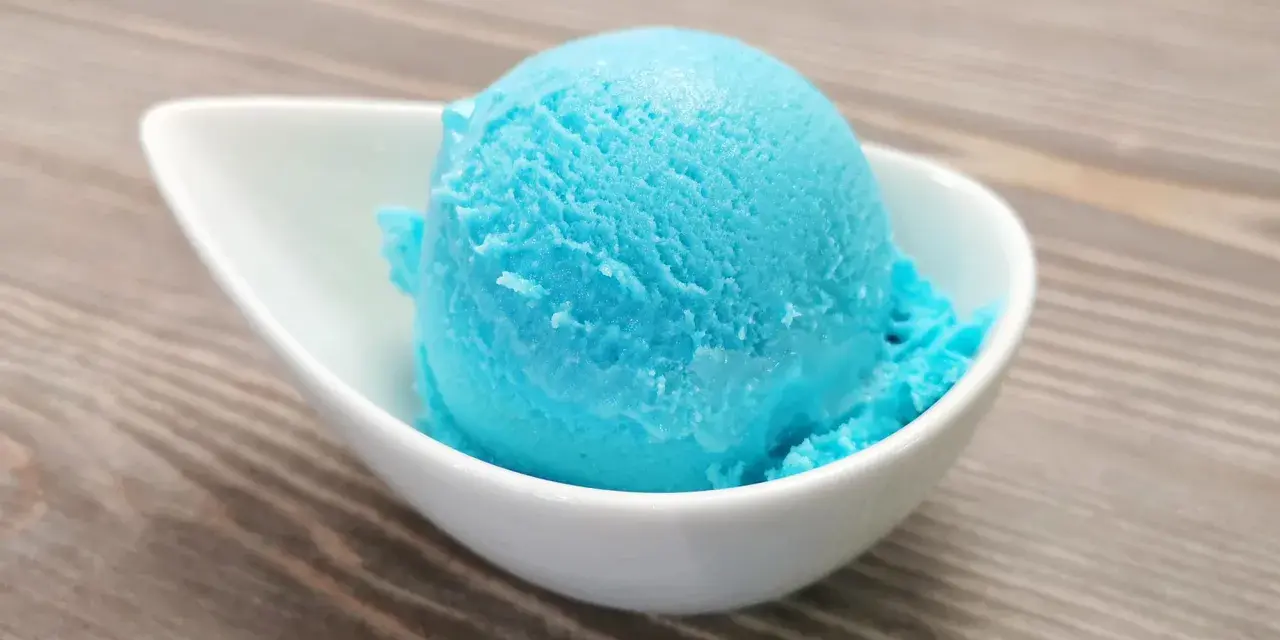 Ein Löffel leuchtend blaues Kaugummi Eis in einer weißen Schale. Perfekt für ein selbstgemachtes Kaugummi Eis Rezept.