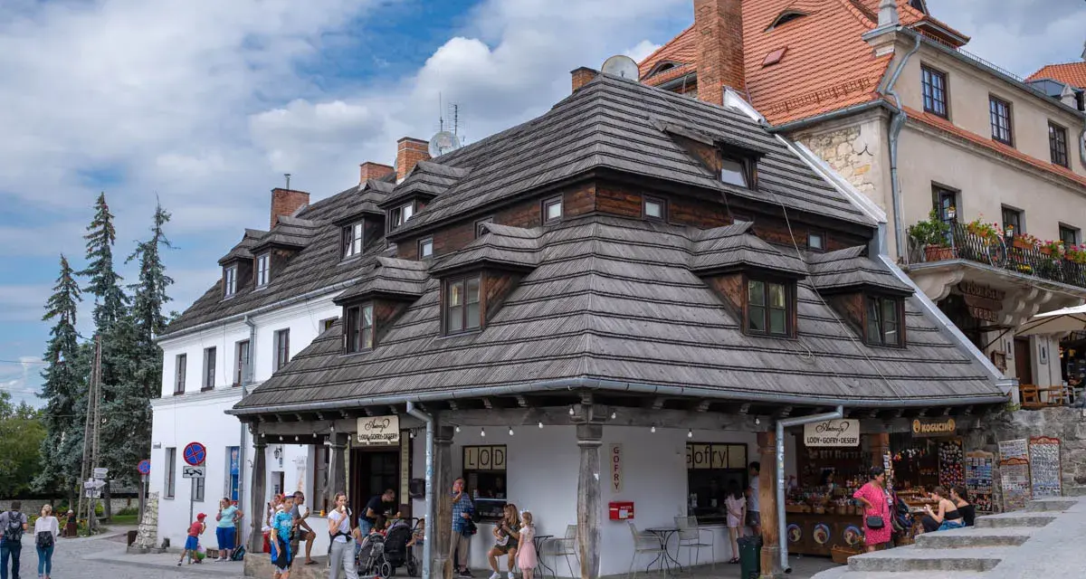 Kazimierz Dolny rynek tętni życiem. Ludzie spacerują, kupują lody i gofry pod urokliwymi, drewnianymi dachami kamienic.