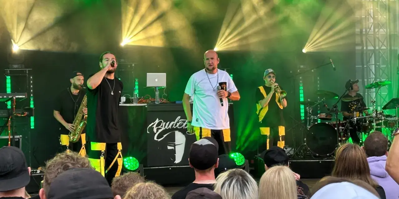 Zespół na scenie podczas festiwalu czochraj bobra fest. Wokalista śpiewa, grają saksofonista, trębacz i perkusista.
