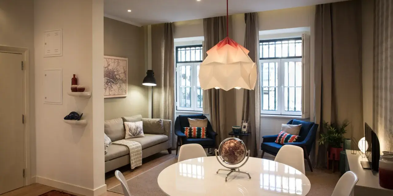 Una sala da pranzo moderna con tavolo bianco, sedie, divano, poltrone blu e un globo decorativo.