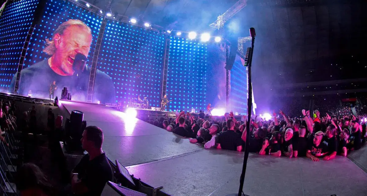 James Hetfield śpiewa na koncercie Metalliki w Warszawie. Tłum szaleje, a gigantyczny ekran pokazuje zbliżenie na wokalistę.
