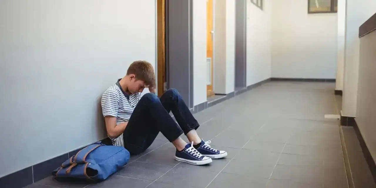 Chłopiec siedzi na korytarzu, przygnębiony. Może potrzebuje pomocy kuratorium?