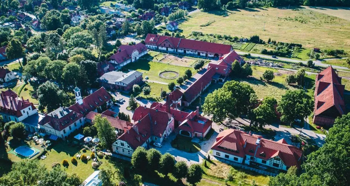 Widok z lotu ptaka na kompleks budynków hotelowych z czerwonymi dachami. Wiele pozytywnych kadyny folwark hotel & spa opinie potwierdza urok tego miejsca.