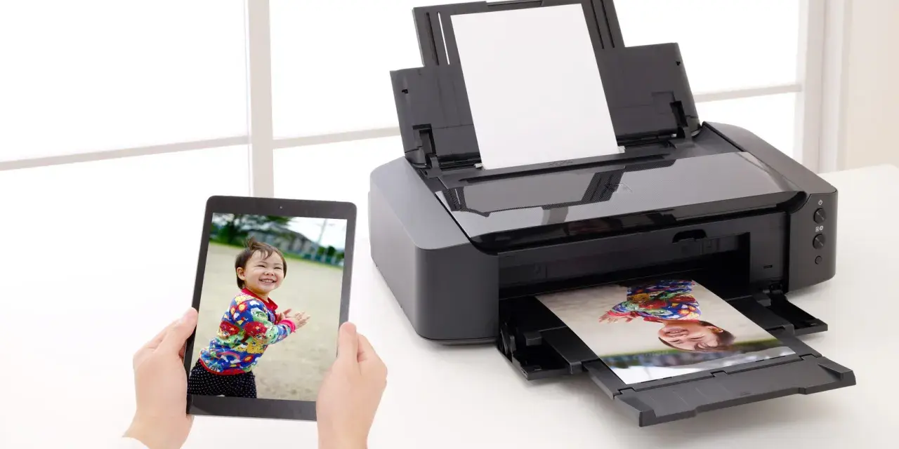 Jak włożyć papier fotograficzny do drukarki? Na tablecie zdjęcie dziecka, drukarka drukuje to samo zdjęcie.