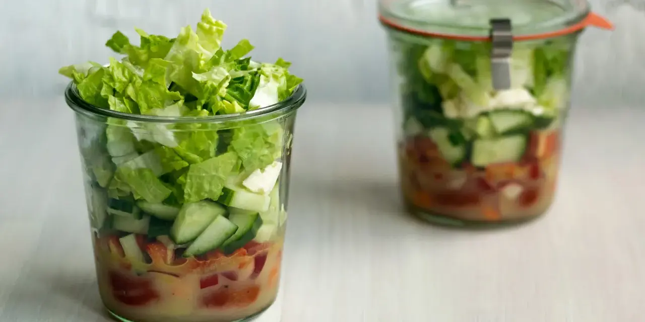 Frischer Salat im Glas, perfekt für eine Party. Schichten aus knackigem Salat, Gurken und Tomaten mit Dressing.