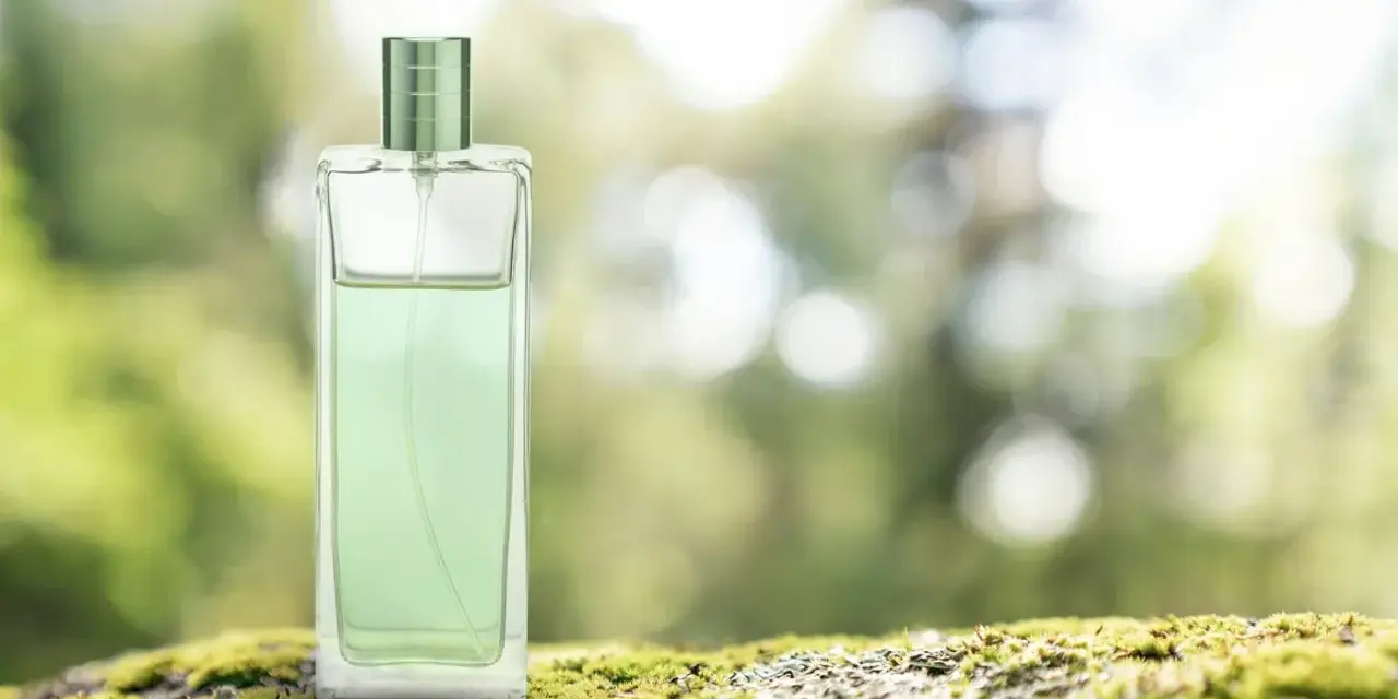Elegancki perfum zielona herbata w szklanej butelce, stojący na mchu.