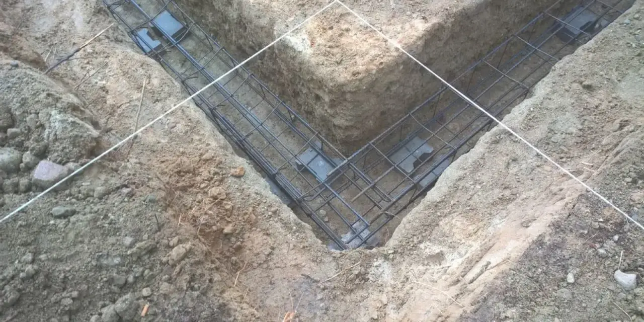 Zbrojenie fundamentów prefabrykowanych w wykopie. Stalowe pręty tworzą siatkę, gotową do zalania betonem.