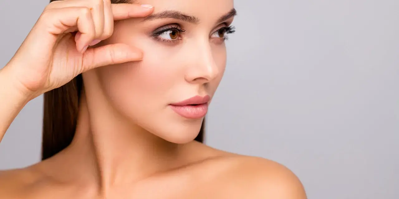 Kobieta bada swoją skórę, która po zabiegu skin booster jest nawilżona i promienna.