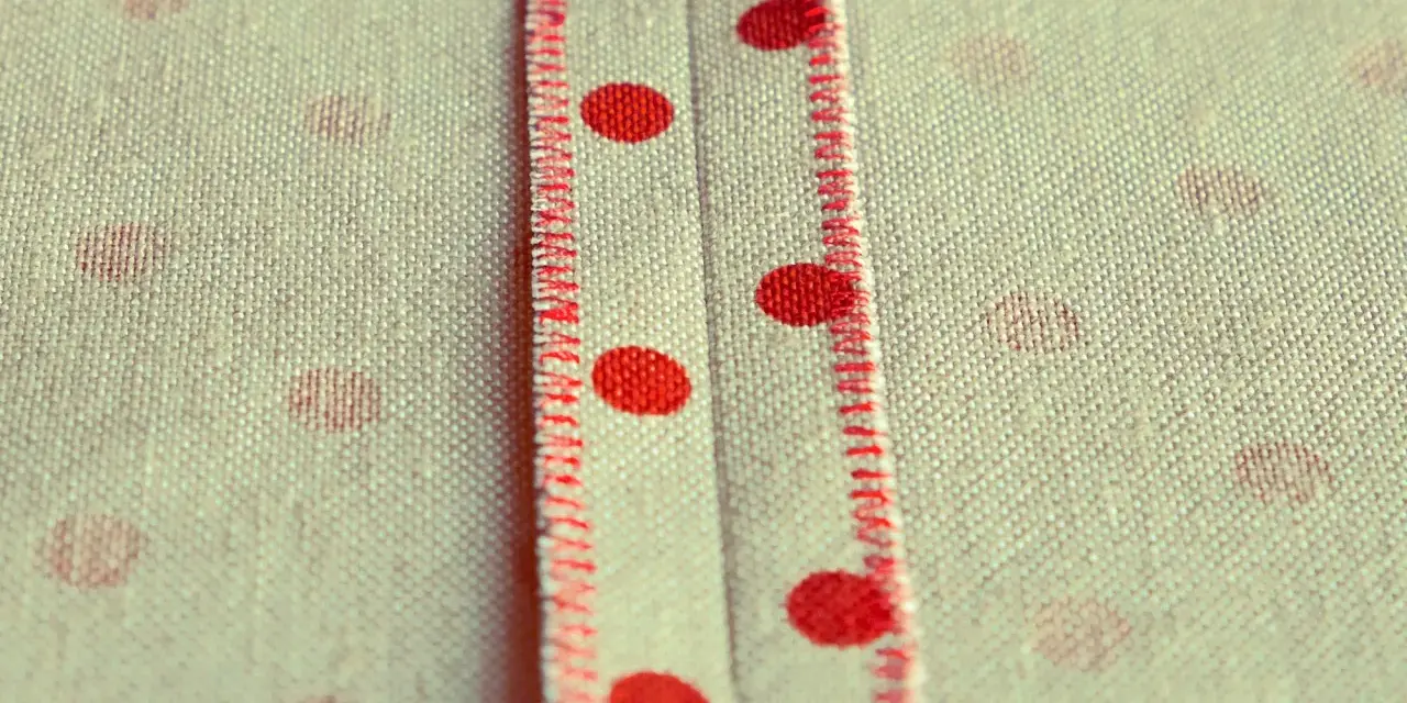Tessuto a pois rossi con cucitura a punto sopraggitto a mano che crea un dettaglio decorativo.