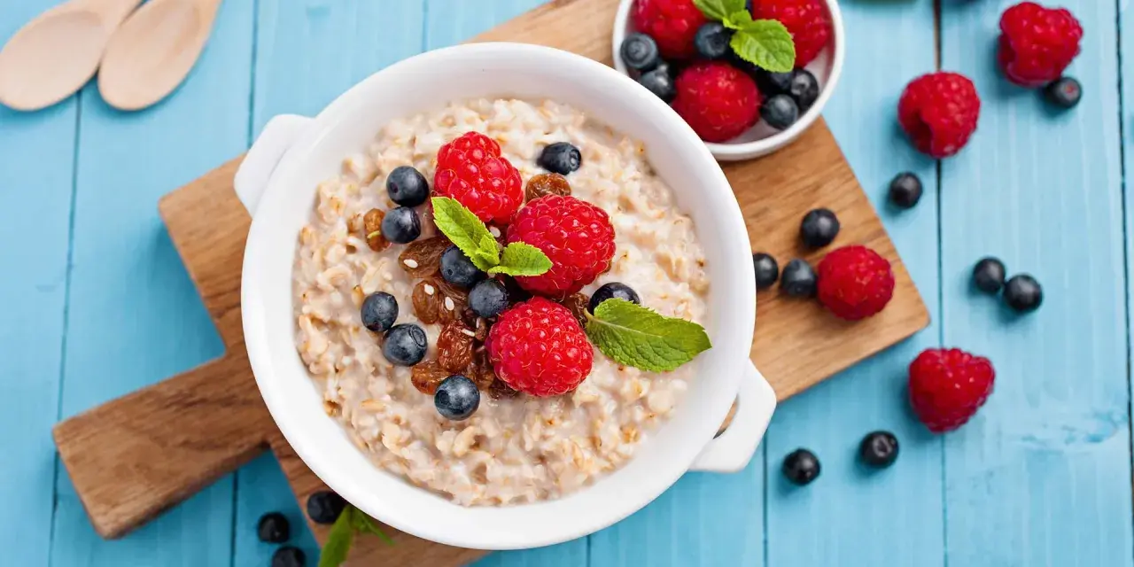 Un tazón de avena con frambuesas, arándanos y pasas. ¡Cuidado! La avena engorda si no se consume con moderación.