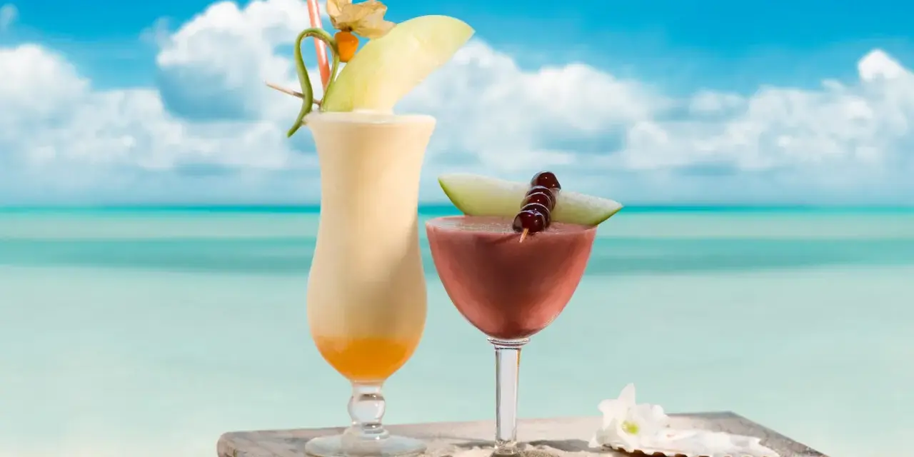 Dwa egzotyczne drinki, jeden kremowy, drugi owocowy, z Malibu na tropikalnej plaży. Idealne na wakacje.