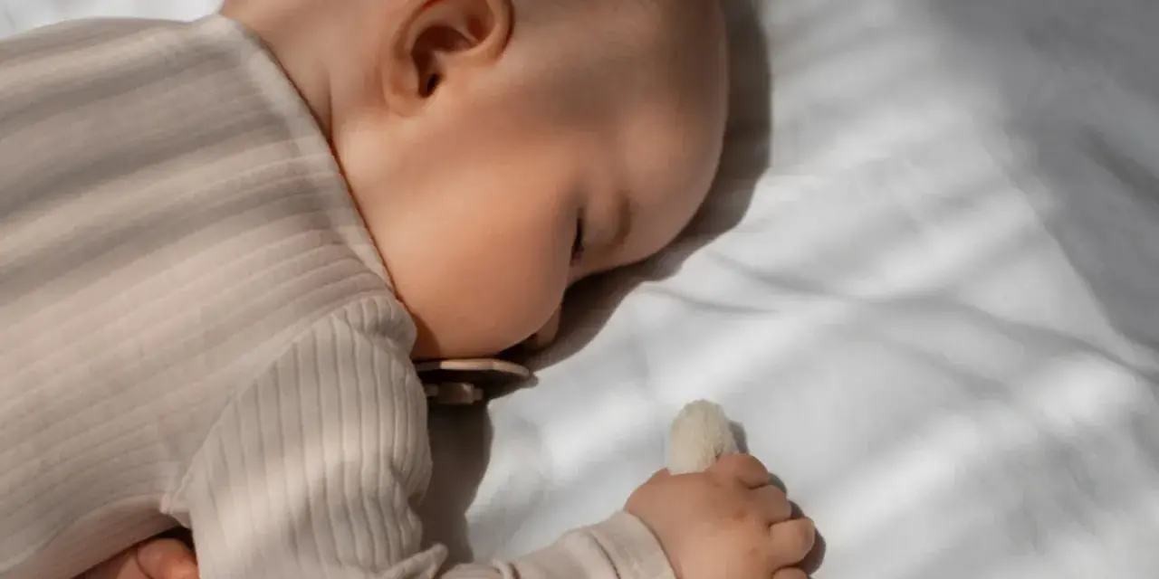 Bambino dorme sereno, forse grazie alla melatonina per bambini iperattivi, con ciuccio e peluche.