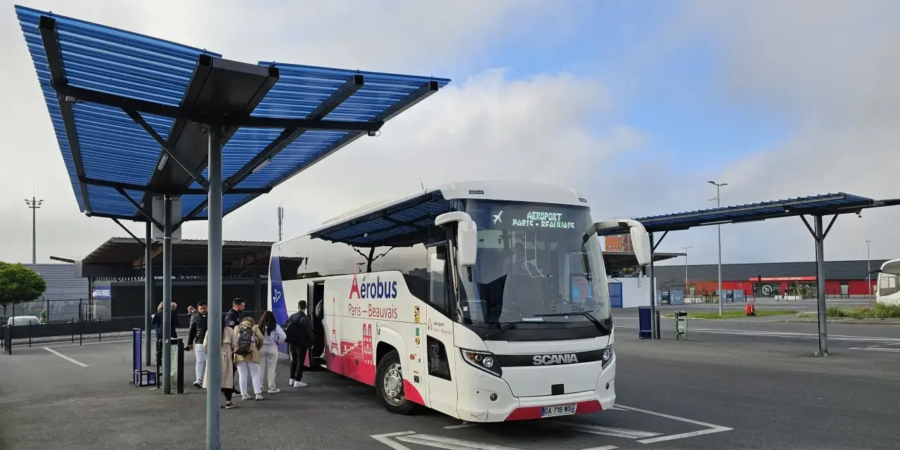 Autobus Aerobus Paris-Beauvais czeka na pasażerów pod niebieskim zadaszeniem.