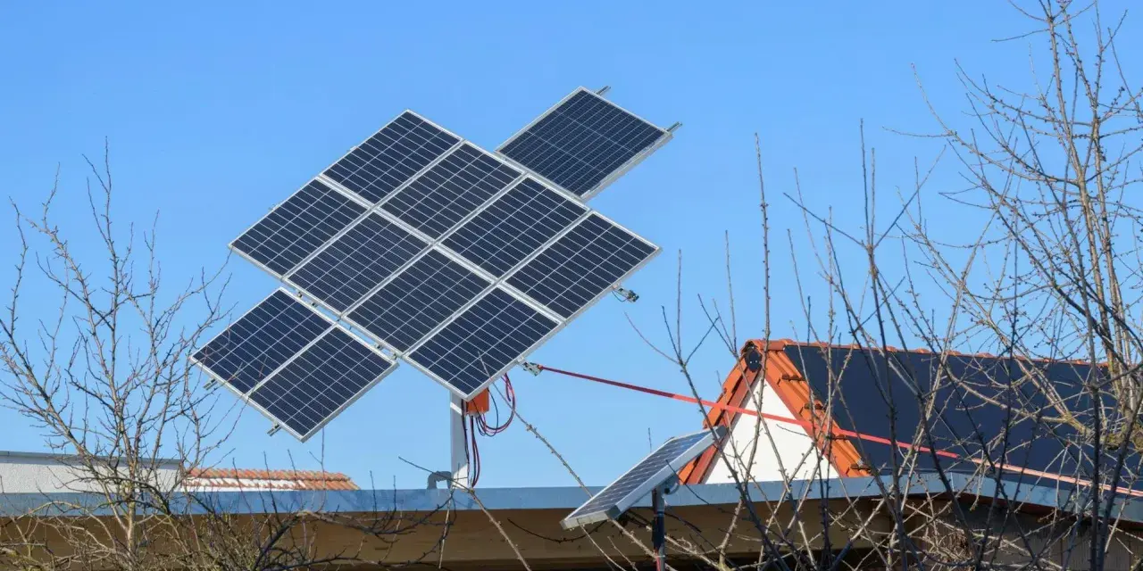 System paneli fotowoltaicznych z trackerem PV, zamontowany na dachu domu, na tle błękitnego nieba.
