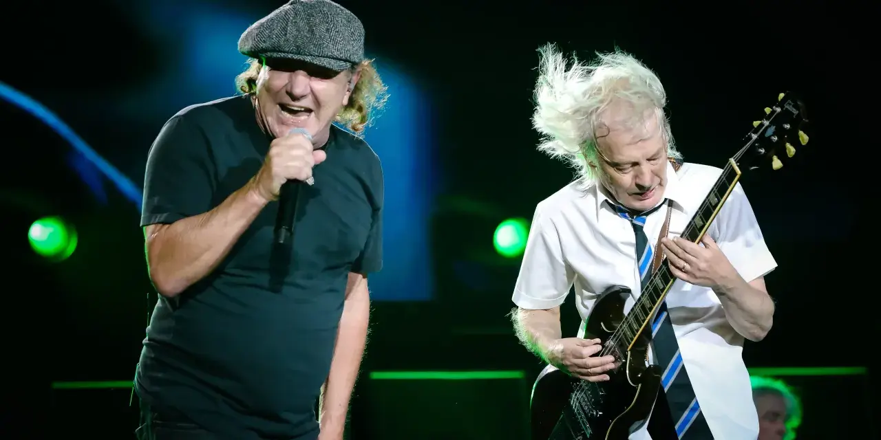 Brian Johnson śpiewa, Angus Young gra na gitarze podczas jednego z legendarnych **AC/DC koncertów**.