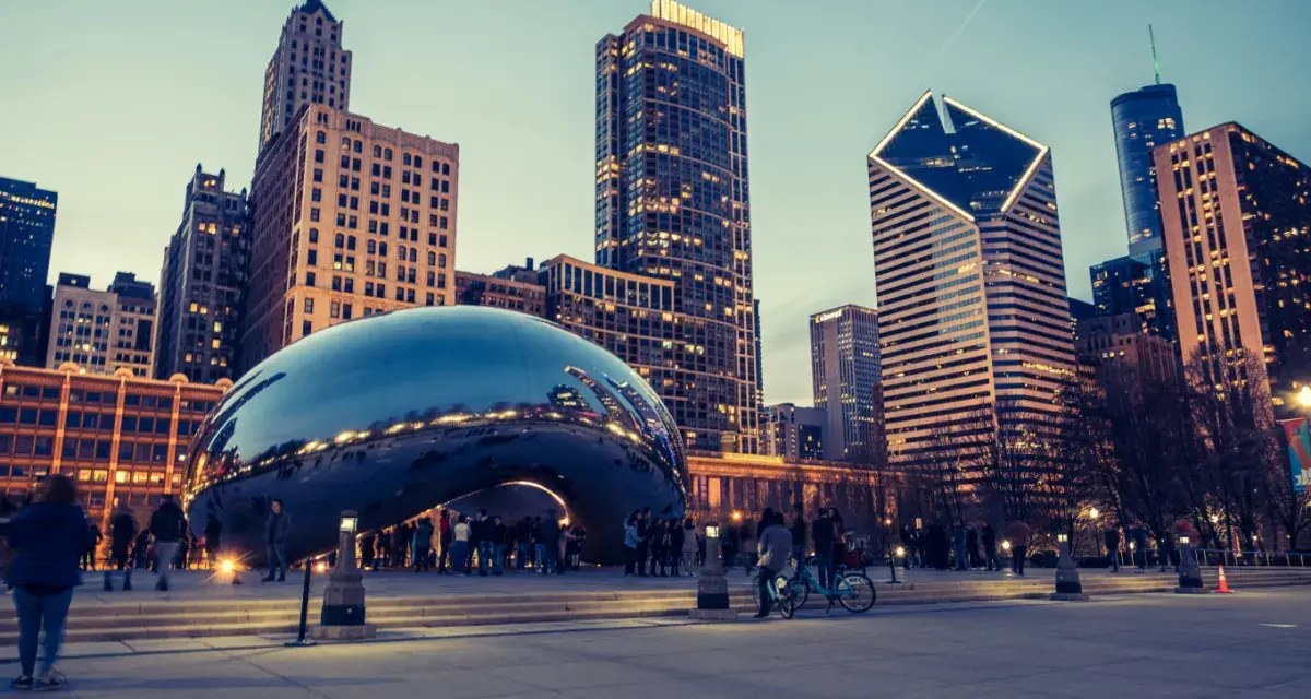 Reflections of the Chicago skyline shimmer on the iconic Cloud Gate sculpture. A perfect snapshot of Chicago in a day, with people enjoying the evening.