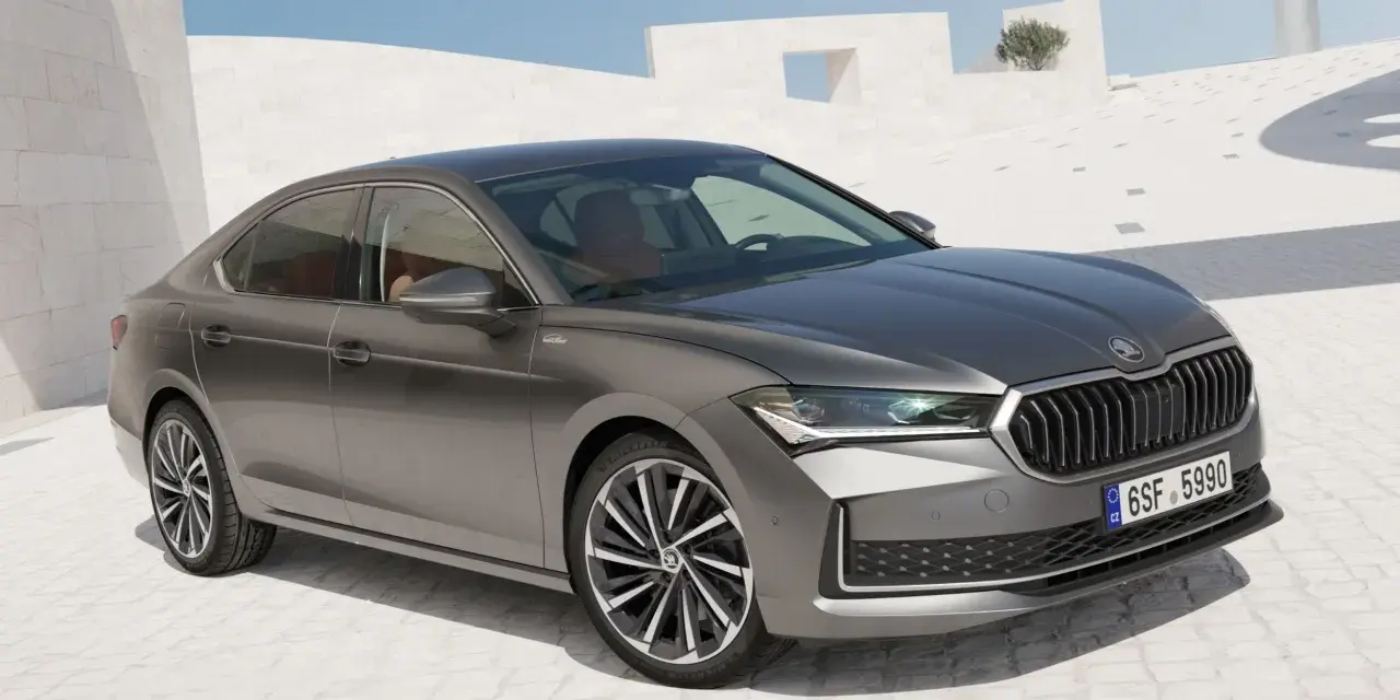 Szary sedan Skoda Superb, segment d, zaparkowany na tle nowoczesnej architektury.
