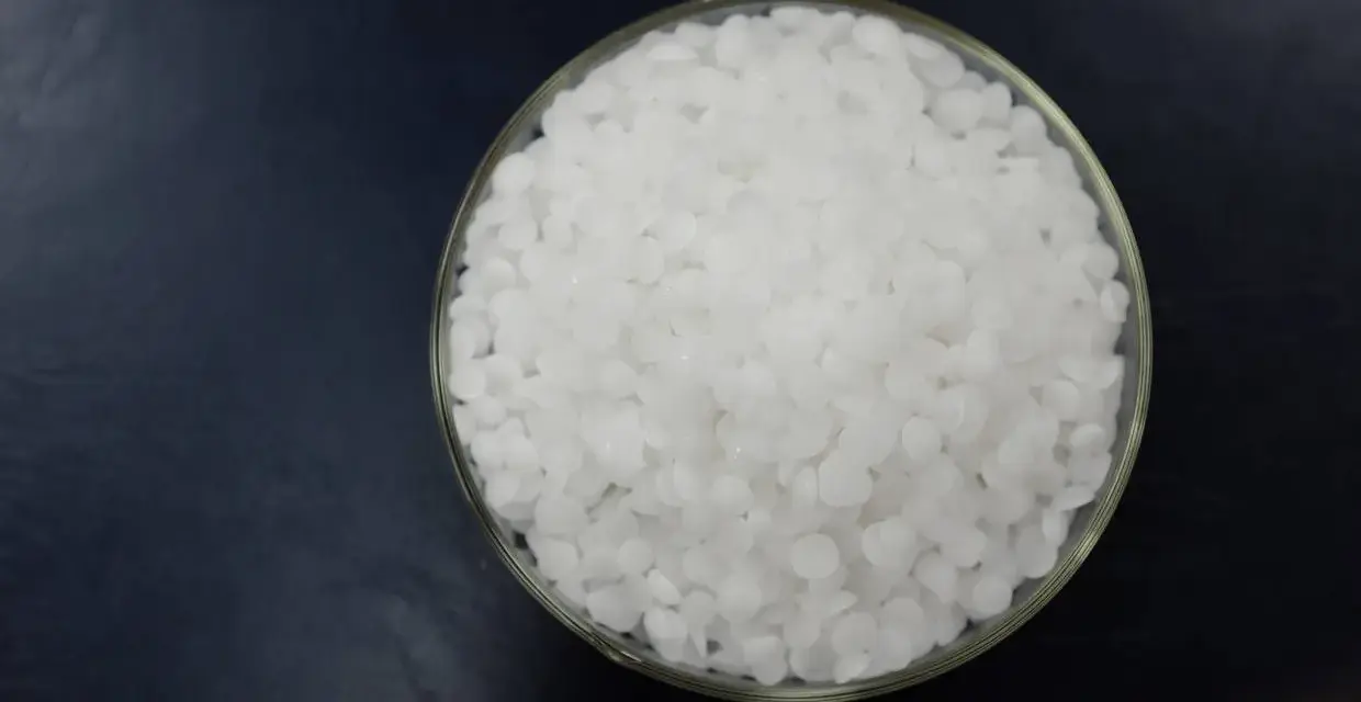 Schale mit weißen Pellets, die Natriumhydroxid darstellen.