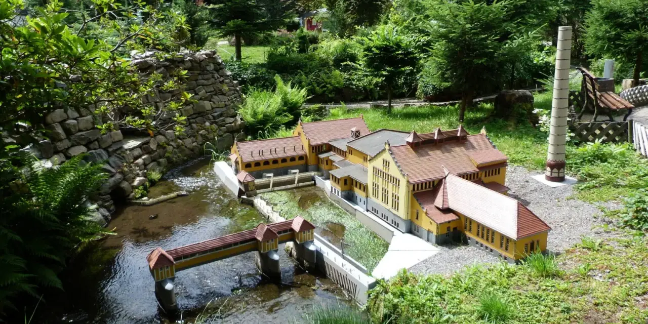 Miniaturowa zabudowa z mostkiem i budynkami, jak w parkach miniatur w Polsce.