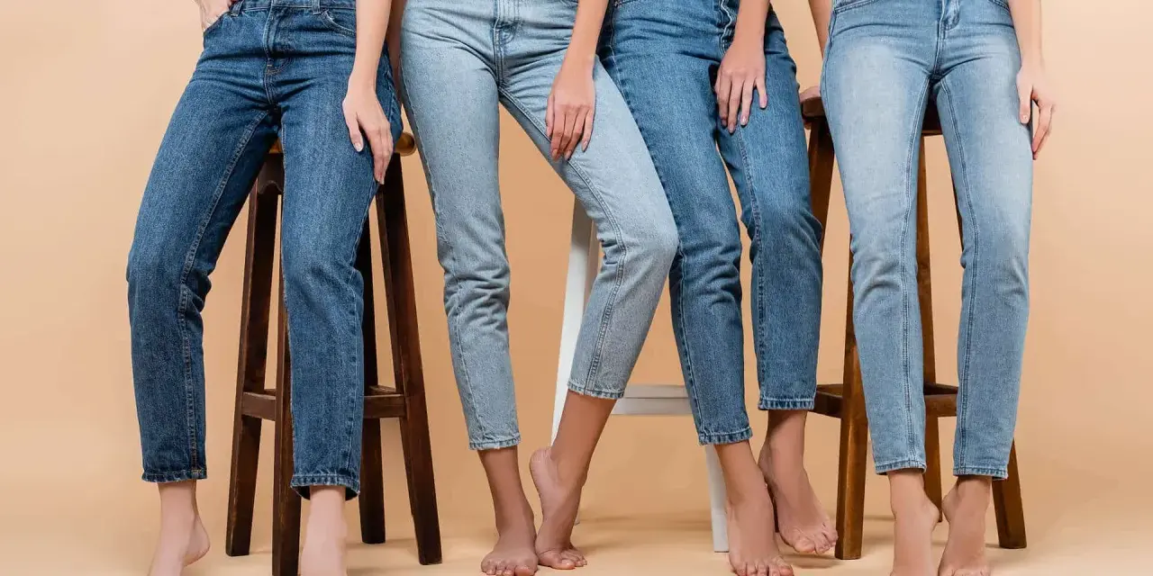 Cztery kobiety w różnych odcieniach jeansów siedzą na stołkach. Denim to materiał, który nigdy nie wychodzi z mody.