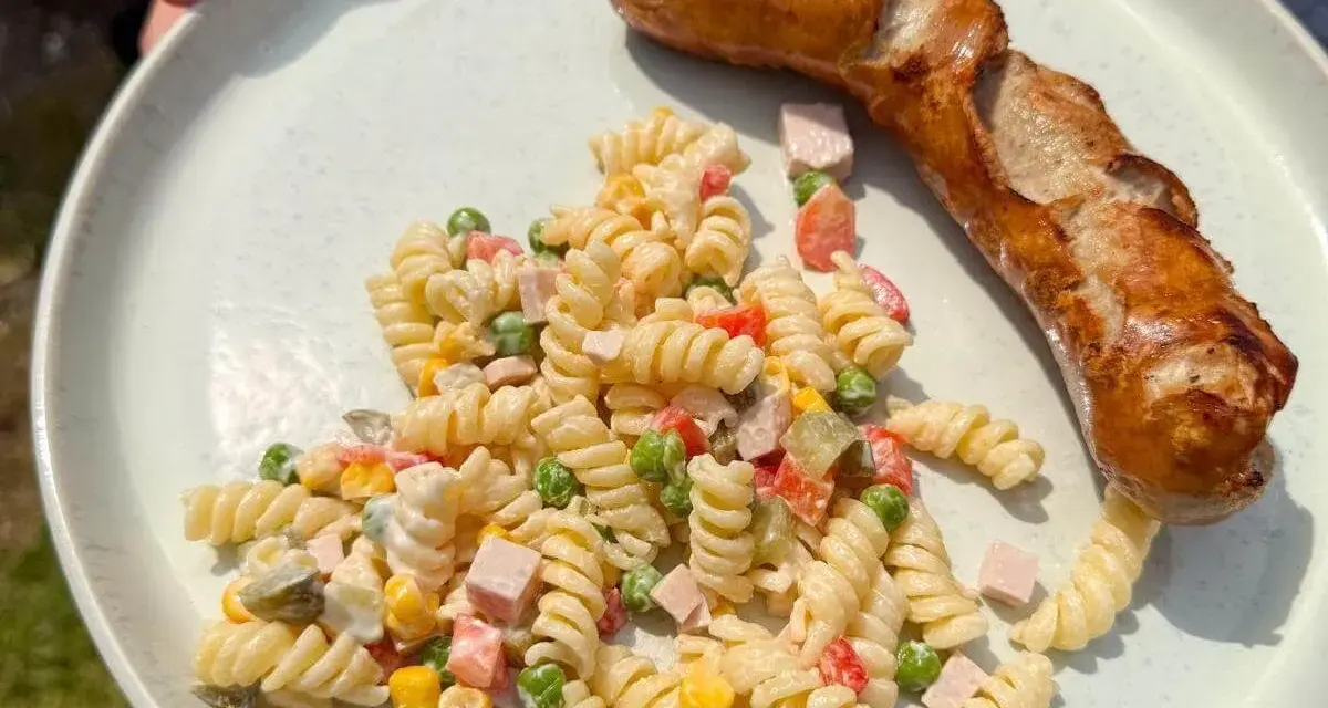Ein herzhafter Nudelsalat mit Erbsen, Mais und Schinken, perfekt als Beilage zu einer gegrillten Wurst. Was passt zu Nudelsalat? Diese Kombination!