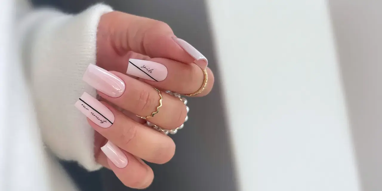 Delikatne, **milky nails** w odcieniach różu, ozdobione czarnymi napisami "smile" i "our moment".