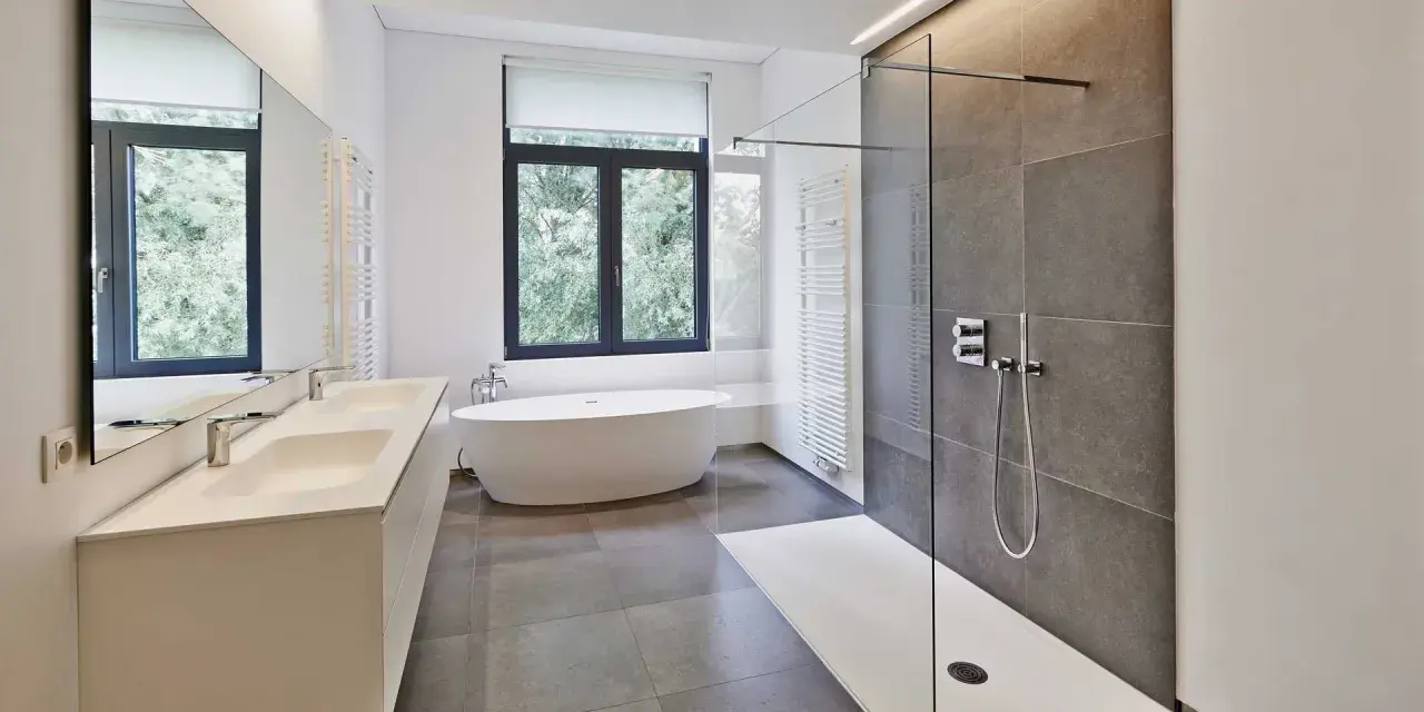 Salle de bain moderne avec douche à l'italienne aux galets hydrofuges, baignoire îlot et double vasque.