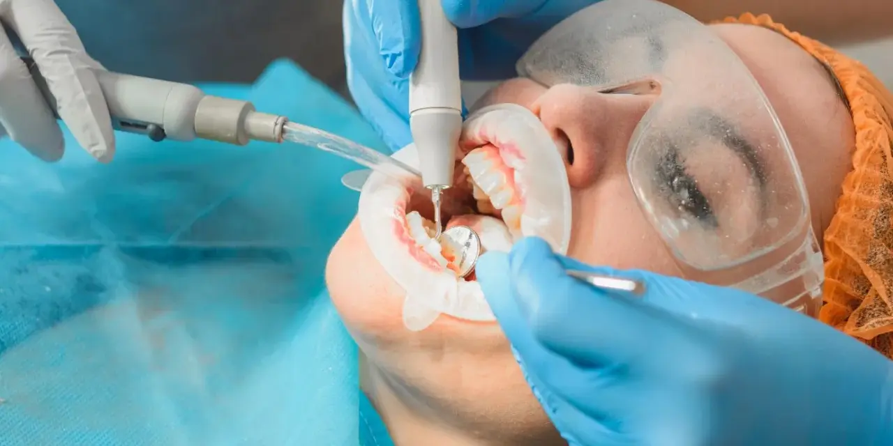 Profesjonalna higienizacja zębów. Dentysta ultradźwiękami usuwa kamień, dbając o zdrowy uśmiech pacjenta.