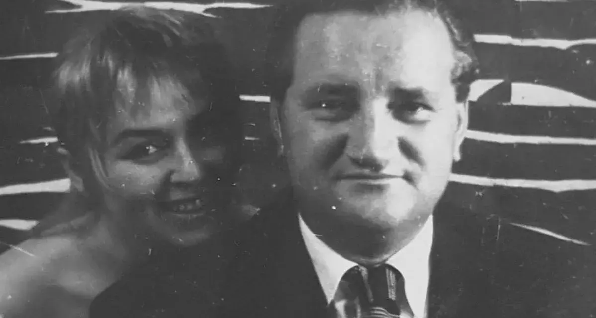 Uśmiechnięta Władysława Nawrocka z mężem, w tle abstrakcyjny wzór.