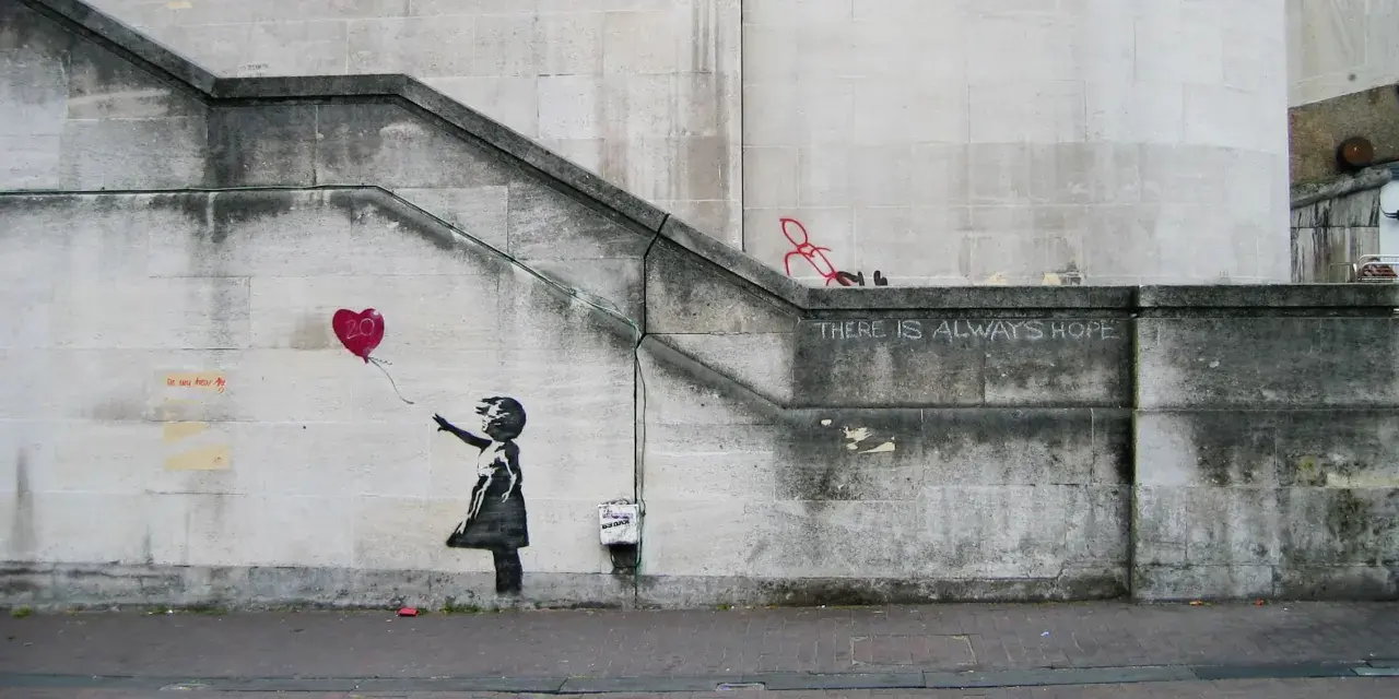 La célèbre œuvre de Banksy, "Girl with Balloon", sur un mur de pierre. Une petite fille lâche un ballon en forme de cœur rouge.