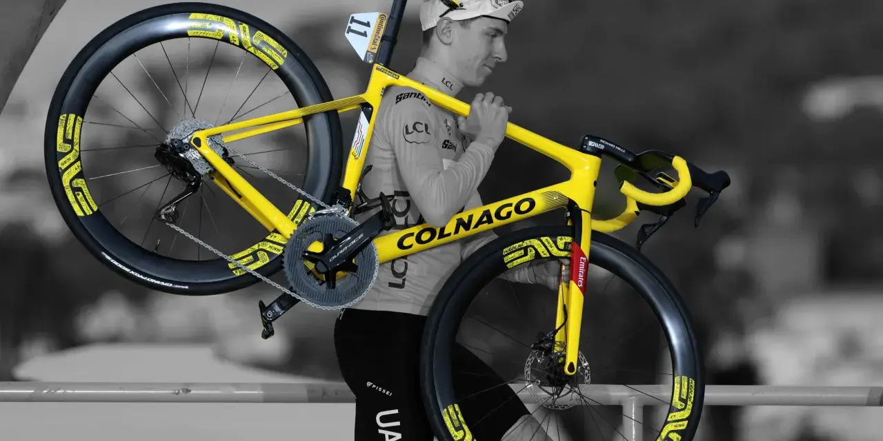 A cyclist carries his bright yellow Colnago bike, ready for Tour de France training.
