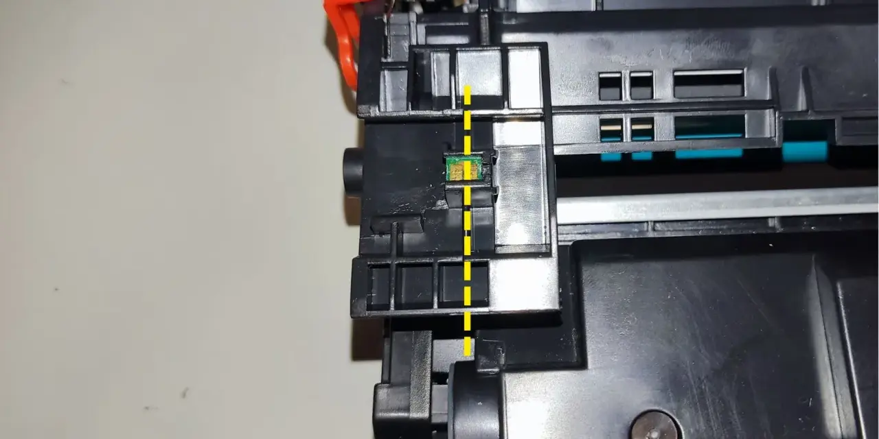 Widok z bliska na chip w tonerze HP, zaznaczony żółtą linią. Pokazuje, jak przełożyć chip w tonerze HP.