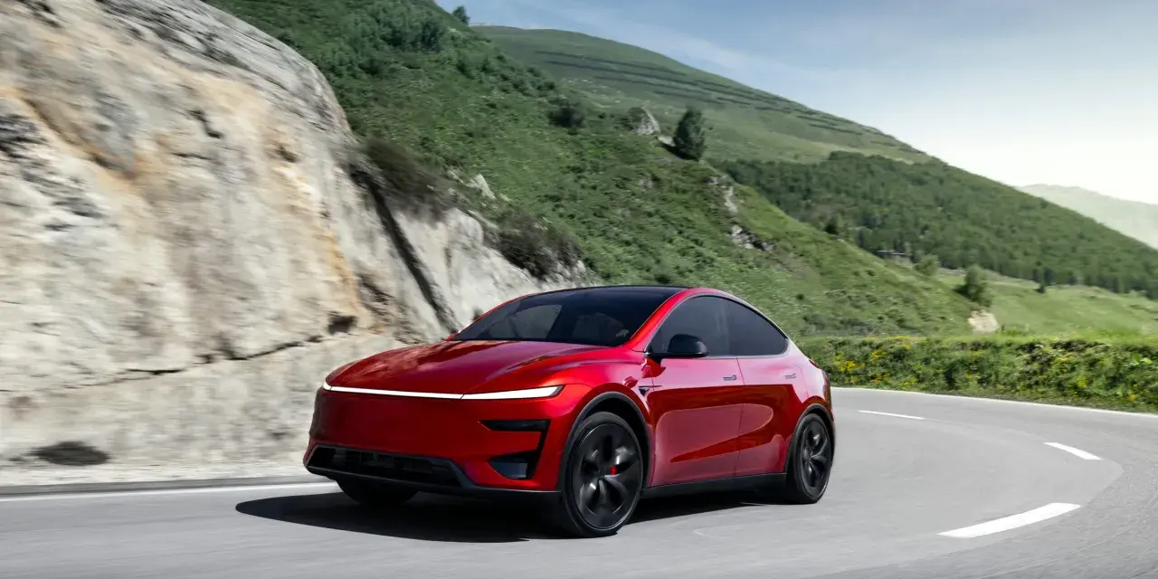 Czerwony Tesla Model Y Performance na krętej drodze w górach.