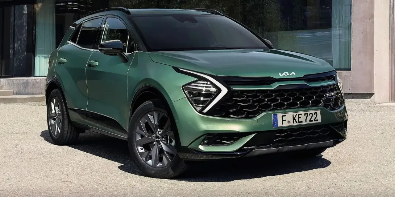 Nowy zielony Kia Sportage 1.6 benzyna z nowoczesnym designem, zaparkowany przed budynkiem.