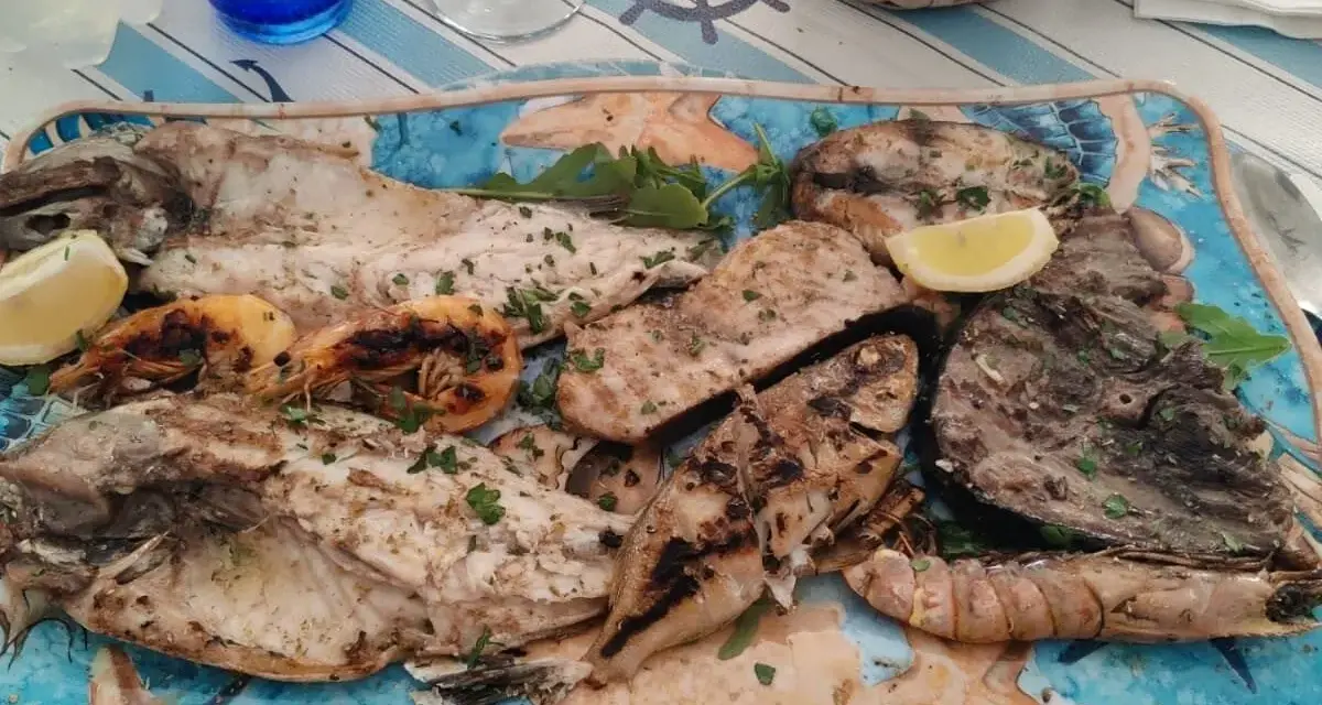 A platter of grilled fish and shrimp garnished with lemon and parsley.